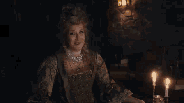 three women are sitting at a table in a dark room and laughing