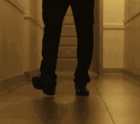 a person walking down a hallway with a shadow of their feet on the floor