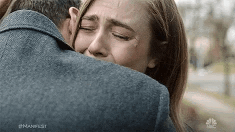 a woman is crying while hugging a man with the hashtag #manifest on the bottom