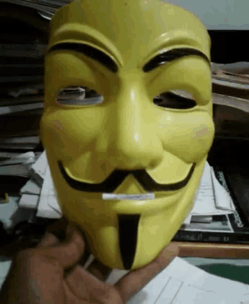 a person is holding a yellow anonymous mask with a mustache