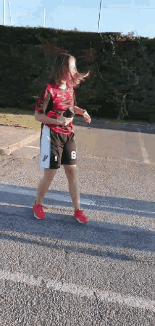 a woman wearing shorts with the number 9 on them is walking down a street