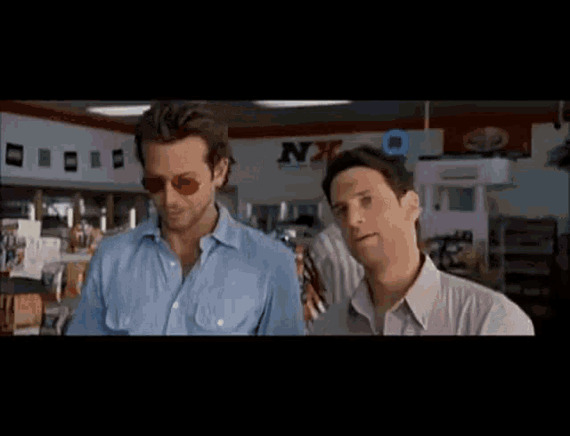 two men are standing in front of a sign that says nx