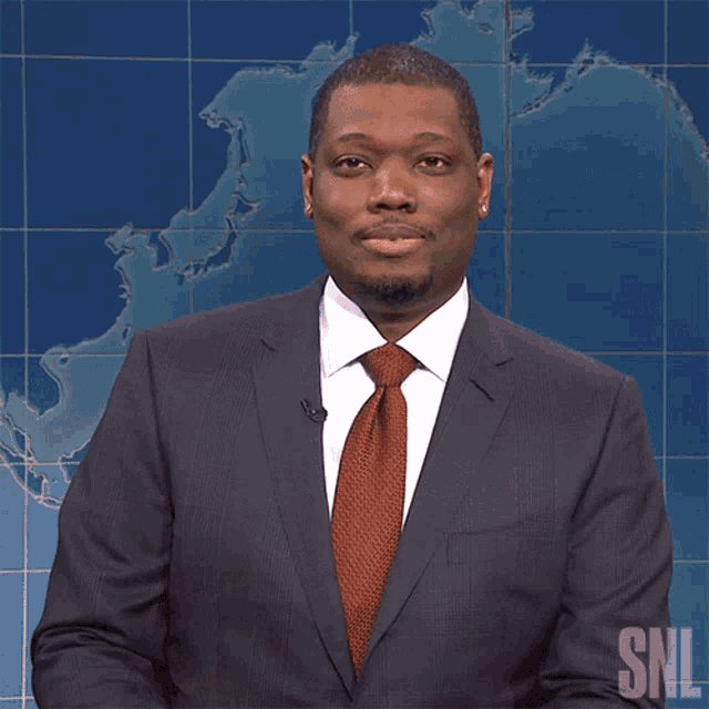 a man in a suit and tie stands in front of a snl map