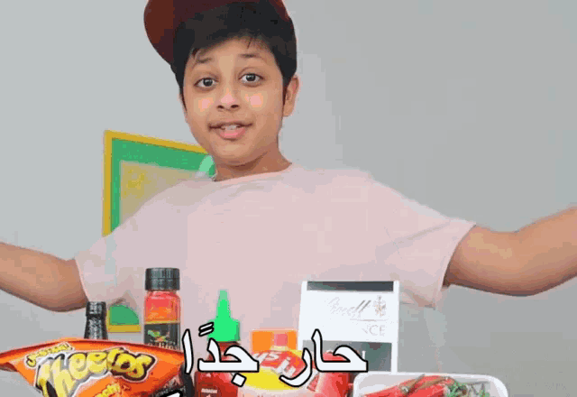 a boy is holding a bag of cheetos and a bottle of chili sauce