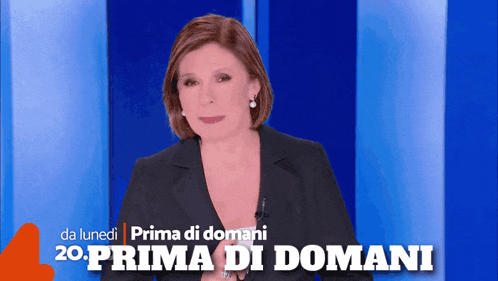 a woman in a suit stands in front of a blue wall with the words prima di domani on it