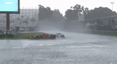 a race car is driving on a wet track in the rain