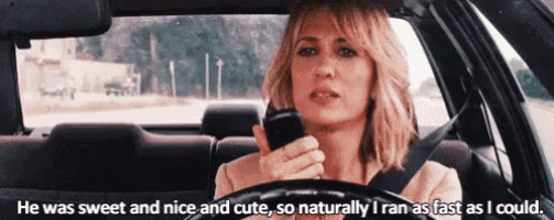 a woman is driving a car while holding a cell phone .