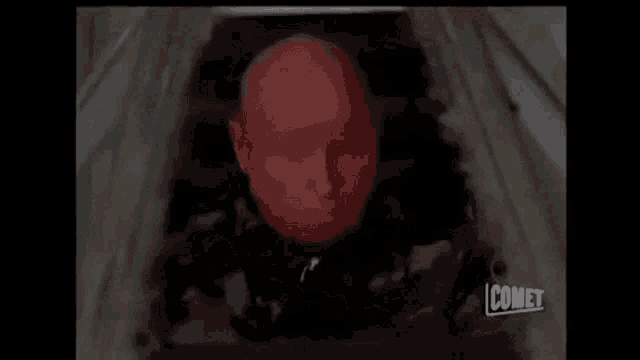 a man is laying in a coffin with a red light coming out of his face .