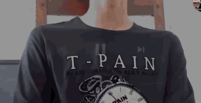 a man wearing a t-pain t-shirt is sitting in a chair