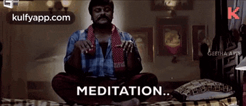 a man is sitting on a bed in a lotus position with the word meditation written on the screen .