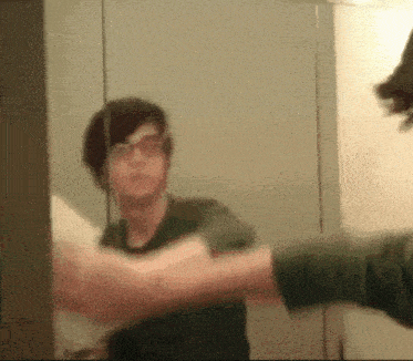 a man in a green shirt is looking at himself in a mirror