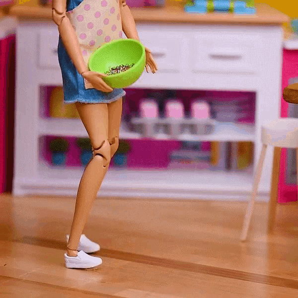 a barbie doll holding a green bowl of cereal