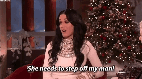 a woman is sitting on a couch in front of a christmas tree and talking to another woman .
