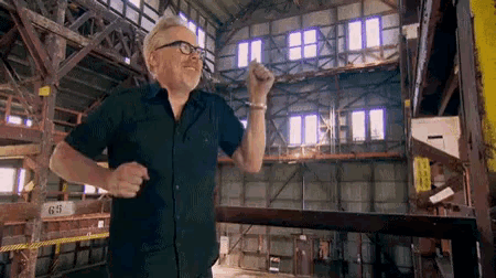 a man in a black shirt and glasses is standing in a large building with the number 65 on it