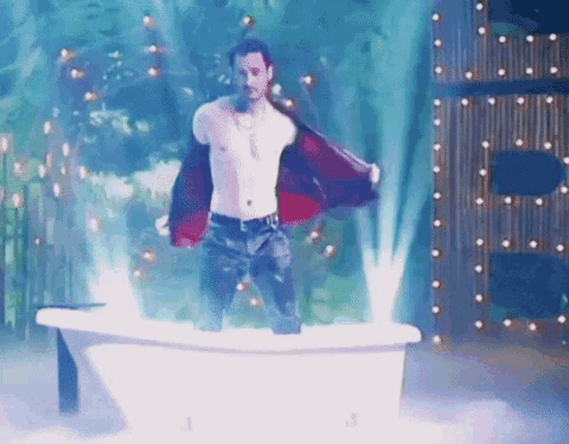 a shirtless man is standing in a bathtub .