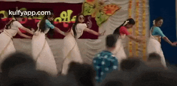a group of women are dancing in front of a crowd in a room .