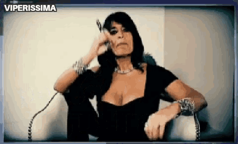 a woman in a black dress is talking on a phone with the words viperissima on the bottom