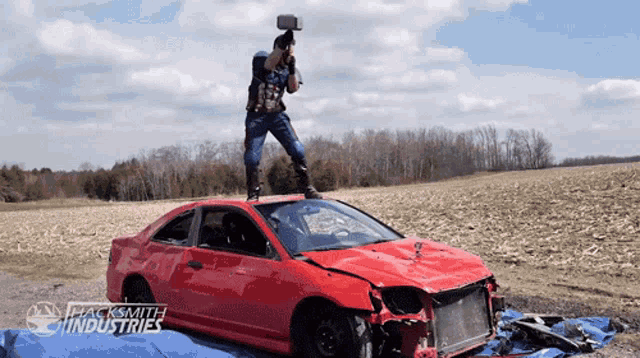 captain america is holding a hammer on top of a smashed car