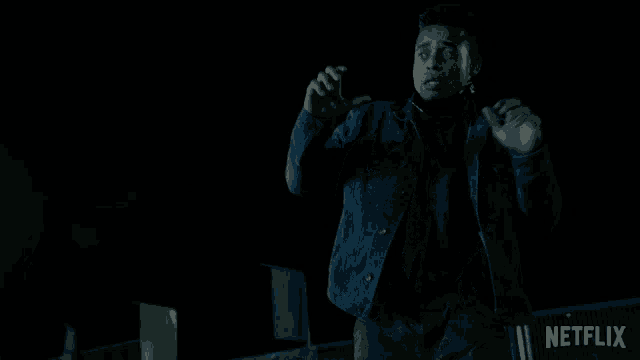 a man in a denim jacket is dancing in front of a netflix sign