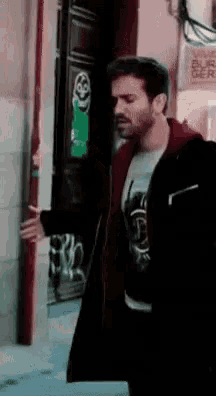 a man in a black jacket is standing in front of a door with a sticker on it that says ' a '