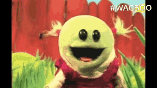 a cartoon character with a big smile on his face is standing in the grass .