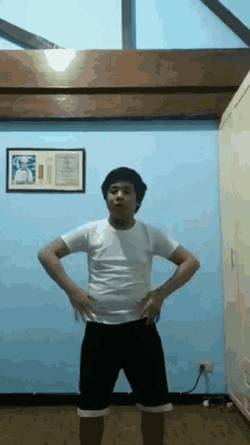 a young man is standing in a room with his hands on his hips .