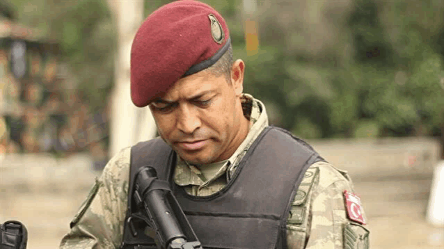 a man in a military uniform is holding a gun and wearing a beret