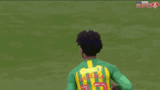 a soccer player in a green and yellow jersey with the number 15 on it