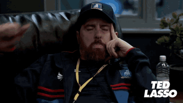 a man in a ted lasso jacket is sitting on a couch