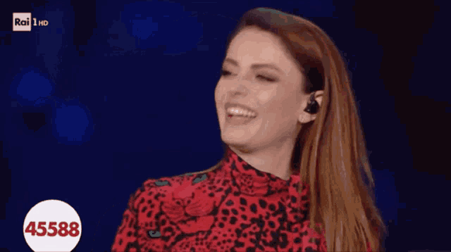 a woman wearing a red leopard print top is smiling with the number 45588 on the bottom