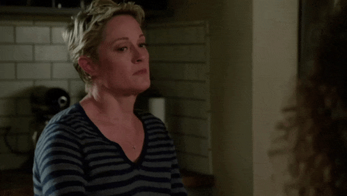 a woman wearing a striped shirt and a necklace looks sad