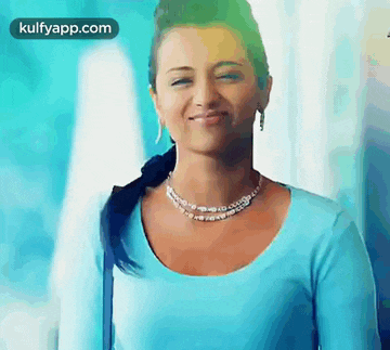 a woman in a blue shirt and necklace is smiling .