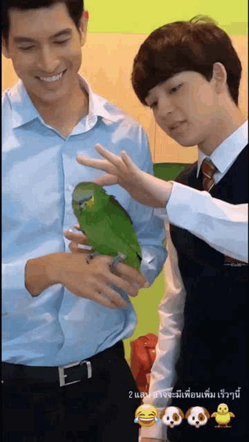 a man holding a green parrot next to another man in a blue shirt and tie