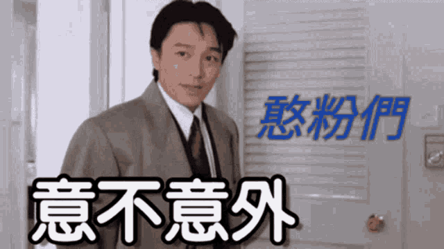 a man in a suit and tie stands in front of a door that has chinese writing on it