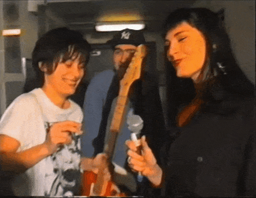 a man wearing a ny hat is playing a guitar