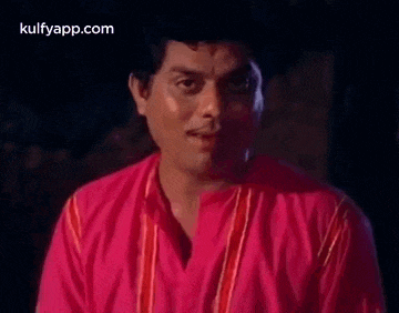 a man in a pink shirt is looking at the camera .