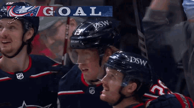 a hockey team celebrates a goal with a banner that says goal