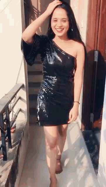 a woman in a black sequined dress is walking down a hallway .