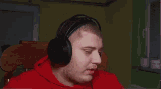 a man wearing headphones is smiling and making a peace sign with his hands .