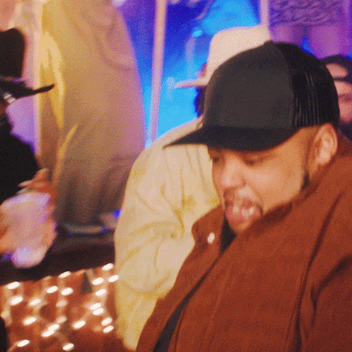 a man wearing a black hat and a brown jacket looks down