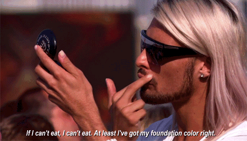 a man with long blonde hair is applying foundation