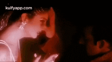 a man and a woman are kissing in a dark room in a movie .