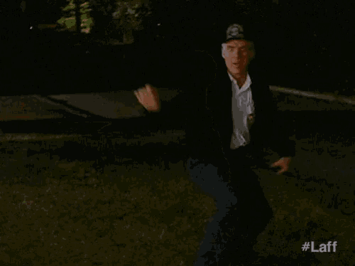a man in a sheriff 's hat is dancing in a park at night .