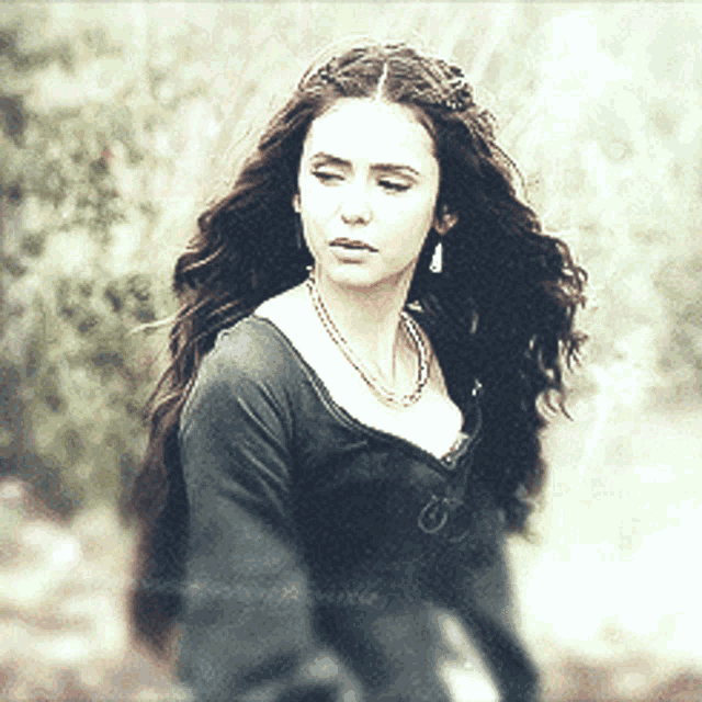 a woman with long dark hair wearing a necklace