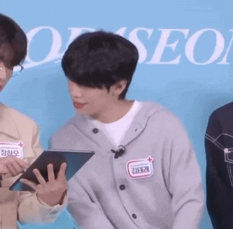 a young man is holding a tablet in his hand while standing next to another man .