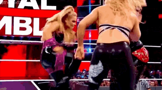 two women are wrestling in a ring with a referee watching .
