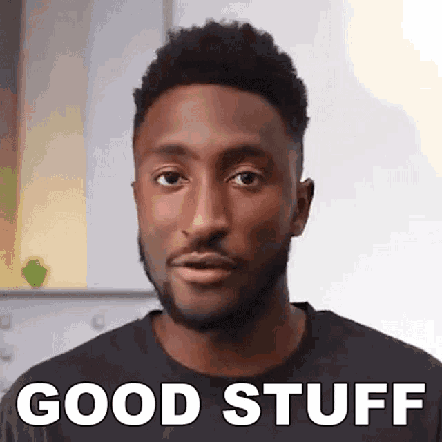 a man with a beard is wearing a black shirt with the words `` good stuff '' on it .
