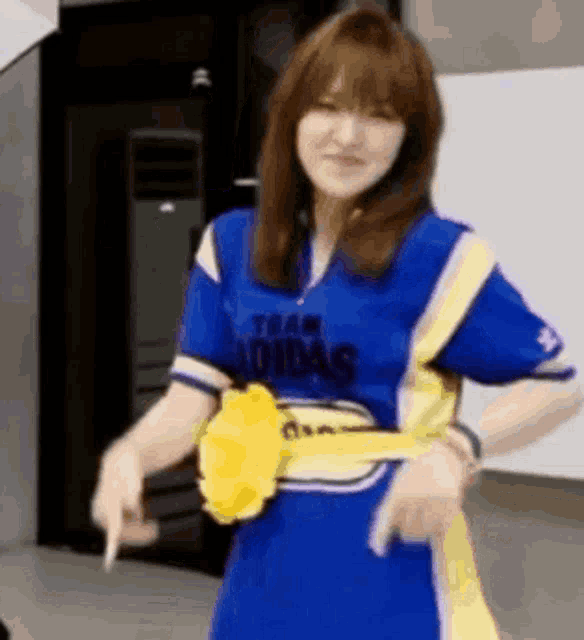 a woman in a blue and yellow adidas shirt is holding a yellow key .