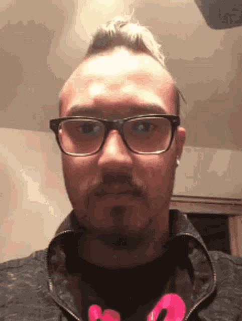 a man with glasses and a ponytail is wearing a black jacket