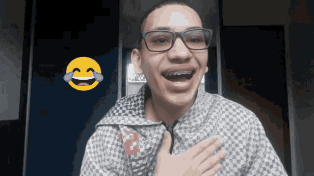 a man with braces on his teeth is laughing with an emoji behind him